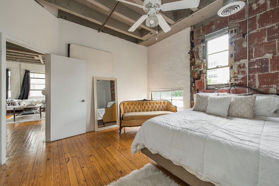 a bedroom with wood floors and exposed brick walls