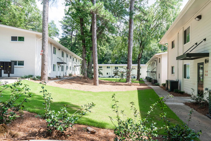 grassy areas with trees next to apartment buildings